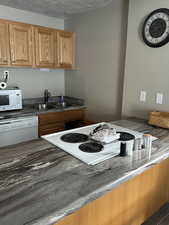 Kitchen featuring a textured ceiling, sink, and white appliances