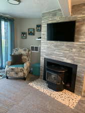 Carpeted living room with a wood stove and a textured ceiling