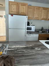 Kitchen featuring white appliances and sink