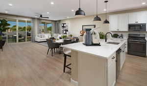 Kitchen featuring a center island with sink, sink, decorative light fixtures, gas stove, and white cabinetryUnder Construction. Pictures of a model for example only. Colors and other features may vary from picture.