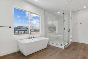 Bathroom featuring a healthy amount of sunlight, a mountain view, wood-type flooring, and shower with separate bathtub