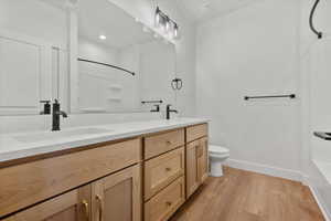 Bathroom featuring hardwood / wood-style floors, vanity, toilet, and a shower