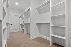 Walk in closet featuring light carpet