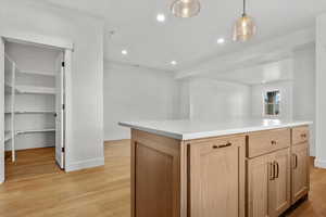 Kitchen with light wood-type flooring, light brown cabinets, a center island, and hanging light fixtures