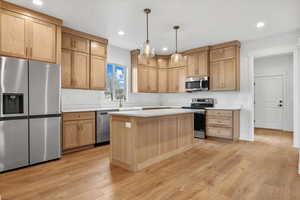 Kitchen with sink, a center island, stainless steel appliances, light hardwood / wood-style flooring, and pendant lighting