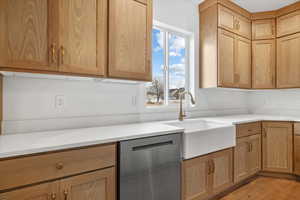 Kitchen featuring light stone counters, dishwasher, light wood-type flooring, and sink