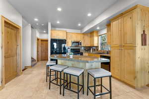 Kitchen with black appliances, a breakfast bar, a kitchen island, and sink