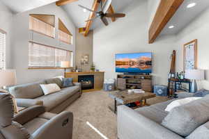 Carpeted great room featuring beamed ceiling, ceiling fan, and high vaulted ceiling