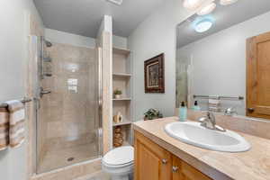 Bathroom featuring vanity, a textured ceiling, toilet, and walk in shower