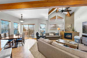 Great room featuring beam ceiling, high vaulted ceiling, ceiling fan, and light tile patterned flooring and carpet