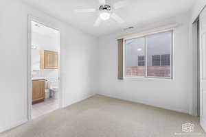 Unfurnished bedroom with ceiling fan, light colored carpet, and connected bathroom