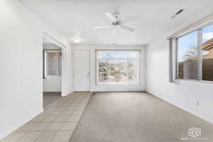 Unfurnished room with plenty of natural light, ceiling fan, and light carpet