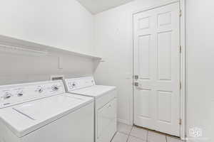 Washroom featuring washer and clothes dryer and light tile patterned flooring