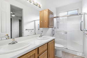 Bathroom with vanity, tile patterned flooring, ceiling fan, toilet, and a shower with shower door