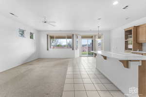 Kitchen featuring ceiling fan, a breakfast bar, light tile patterned floors, and decorative light fixtures