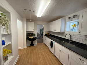 Kitchen featuring white cabinetry, sink, dishwasher, and dark stone counters