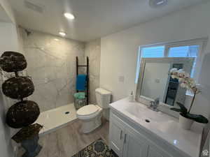 Bathroom featuring vanity, toilet, wood-type flooring, and tiled shower