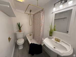 Full bathroom with a textured ceiling, shower / bath combo with shower curtain, sink, wood-type flooring, and toilet