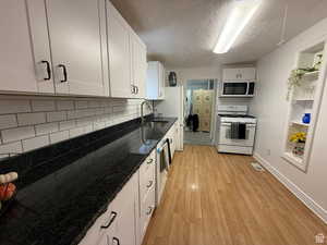 Kitchen featuring tasteful backsplash, sink, light hardwood / wood-style flooring, white cabinets, and white gas stove