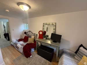 Bedroom with stacked washer and clothes dryer, light hardwood / wood-style flooring, and a textured ceiling