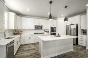 Kitchen featuring stainless steel appliances, a kitchen island, and white cabinetry