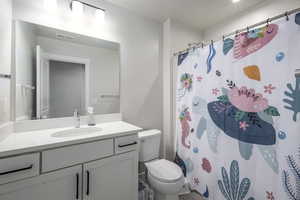 Bathroom with a shower with curtain, vanity, and toilet