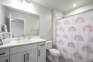 Bathroom with a shower with shower curtain, vanity, and toilet