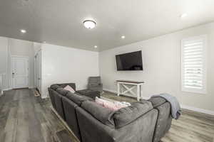 Living room with hardwood / wood-style floors, a textured ceiling, and plenty of natural light