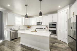 Kitchen featuring a center island, white cabinets, pendant lighting, and appliances with stainless steel finishes