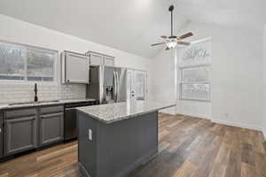 Kitchen featuring stainless steel fridge, tasteful backsplash, sink, dishwasher, and a center island