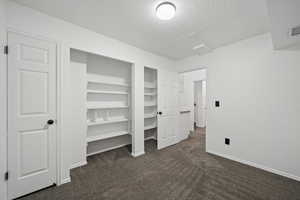 Unfurnished bedroom featuring dark colored carpet and a textured ceiling