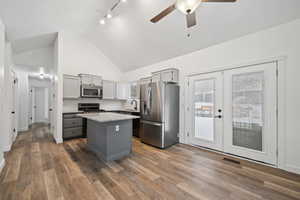 Kitchen with gray cabinetry, french doors, decorative backsplash, a kitchen island, and appliances with stainless steel finishes