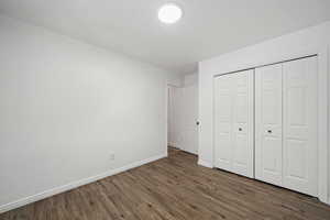 Unfurnished bedroom with dark hardwood / wood-style flooring and a closet