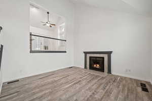 Unfurnished living room with a tile fireplace, ceiling fan, light hardwood / wood-style floors, and lofted ceiling