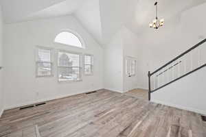 Foyer featuring light hardwood / wood-style flooring, high vaulted ceiling, and an inviting chandelier