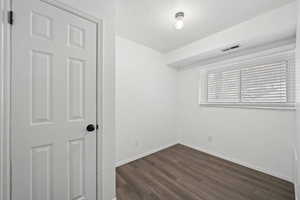 Unfurnished room with a textured ceiling and dark hardwood / wood-style floors