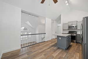 Kitchen featuring gray cabinets, a kitchen island, backsplash, and appliances with stainless steel finishes