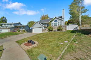 View of front of property with a fire pit, a garage, and a front lawn