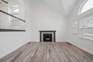 Unfurnished living room with a fireplace, high vaulted ceiling, and light hardwood / wood-style floors