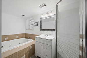 Bathroom featuring vanity, a textured ceiling, and tiled bath