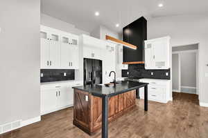 Kitchen featuring a kitchen island with sink, white cabinets