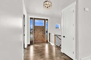 Entrance foyer featuring dark hardwood / wood-style floors and a notable chandelier