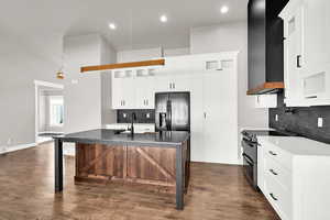 Kitchen featuring a kitchen island with sink, range with two ovens,  and white cabinetry