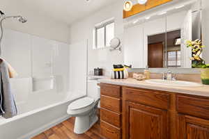 Full bathroom featuring hardwood / wood-style flooring, vanity,  shower combination, and toilet