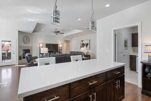 Kitchen featuring pendant lighting, a center island, dark wood-type flooring, ceiling fan, and a tray ceiling