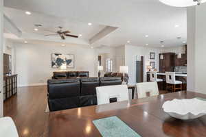 Dining area featuring a tray ceiling, ceiling fan, and dark hardwood / wood-style flooring