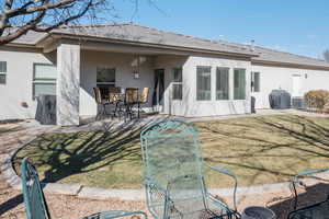 Rear view of house with central AC unit, a patio area, and a lawn