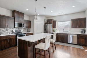 Kitchen featuring appliances with stainless steel finishes, a center island, and dark brown cabinetry