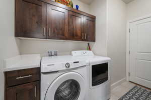 Clothes washing area featuring washer and dryer and cabinets