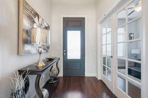 Foyer entrance with ceiling fan, dark wood-type flooring, and french doors